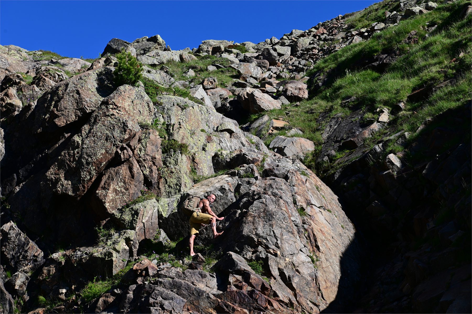 Claudio Lombardo avanza a piedi nudi lungo un passaggio naturale tra rocce e pendio erboso