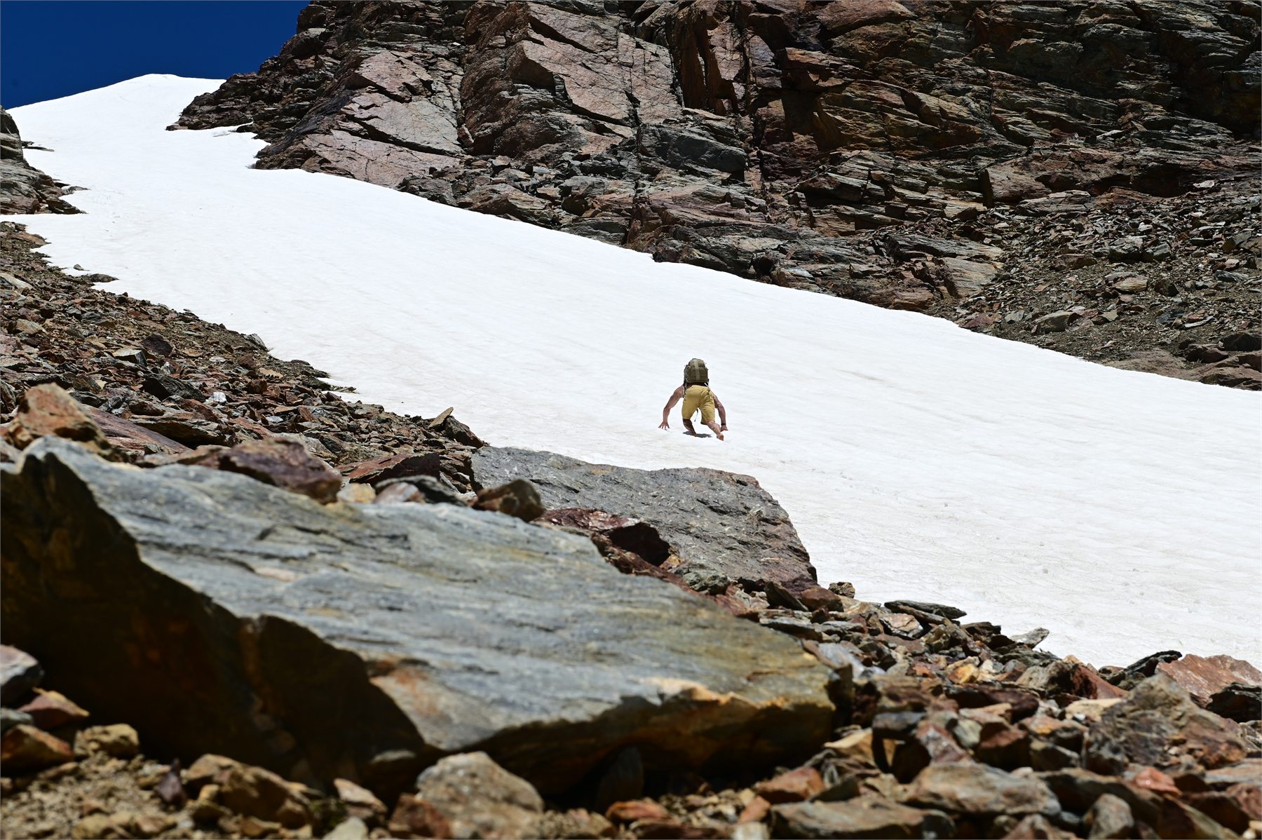 Claudio Lombardo procede a piedi nudi su un nevaio circondato da pareti rocciose