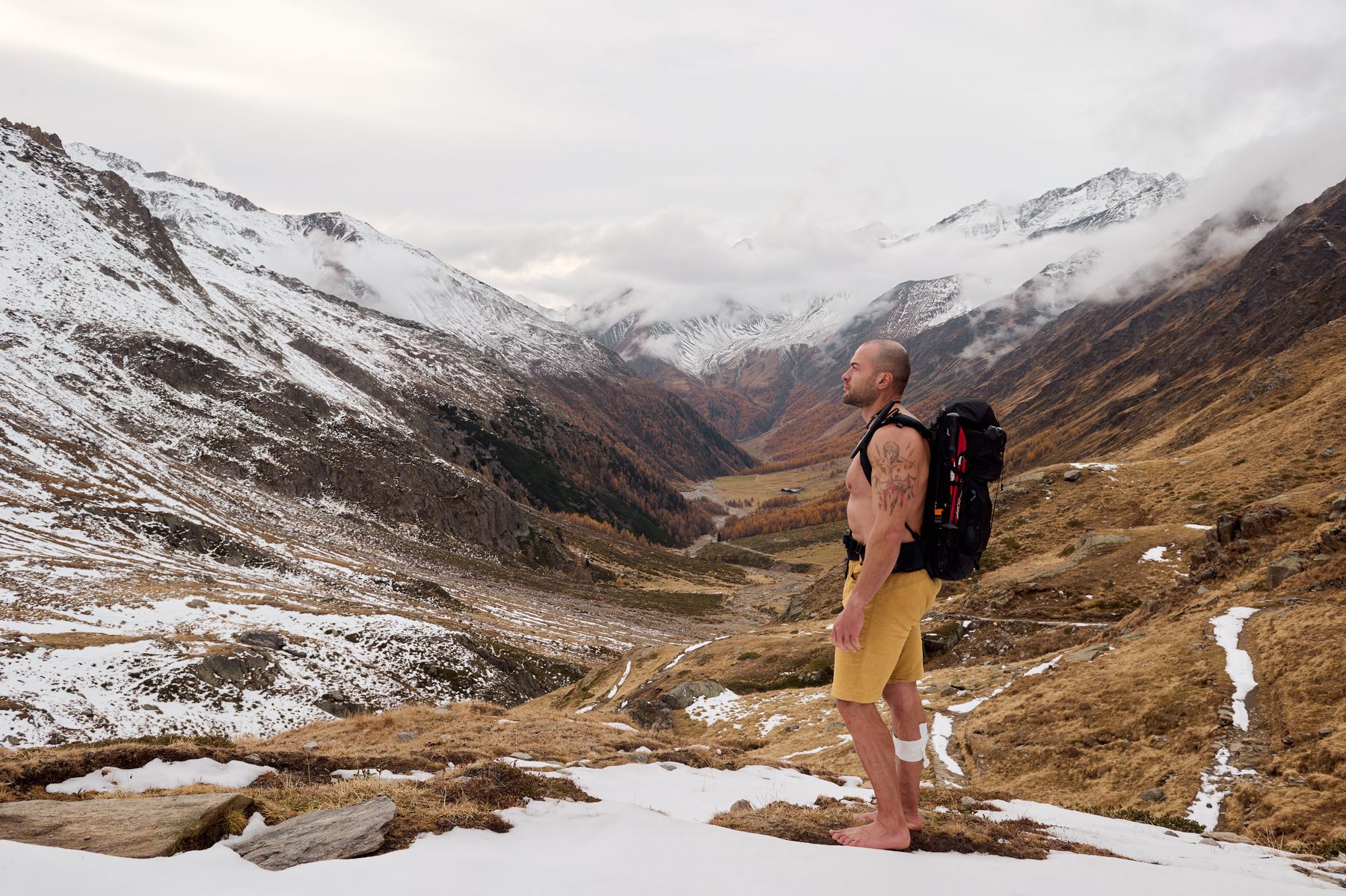 Claudio Lombardo in piedi a piedi nudi davanti a una valle parzialmente innevata