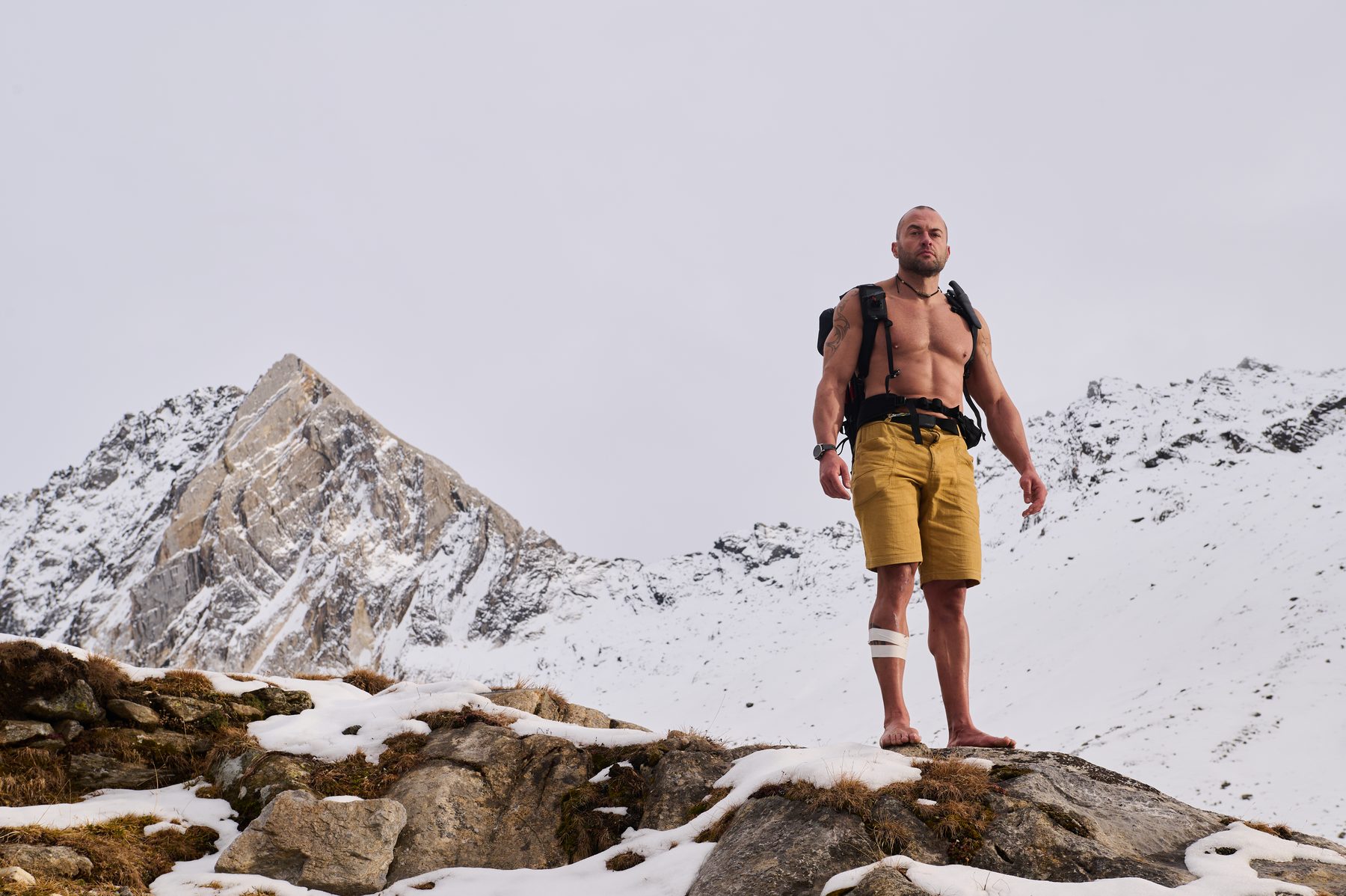 Claudio Lombardo in piedi a piedi nudi su una roccia davanti alle cime innevate