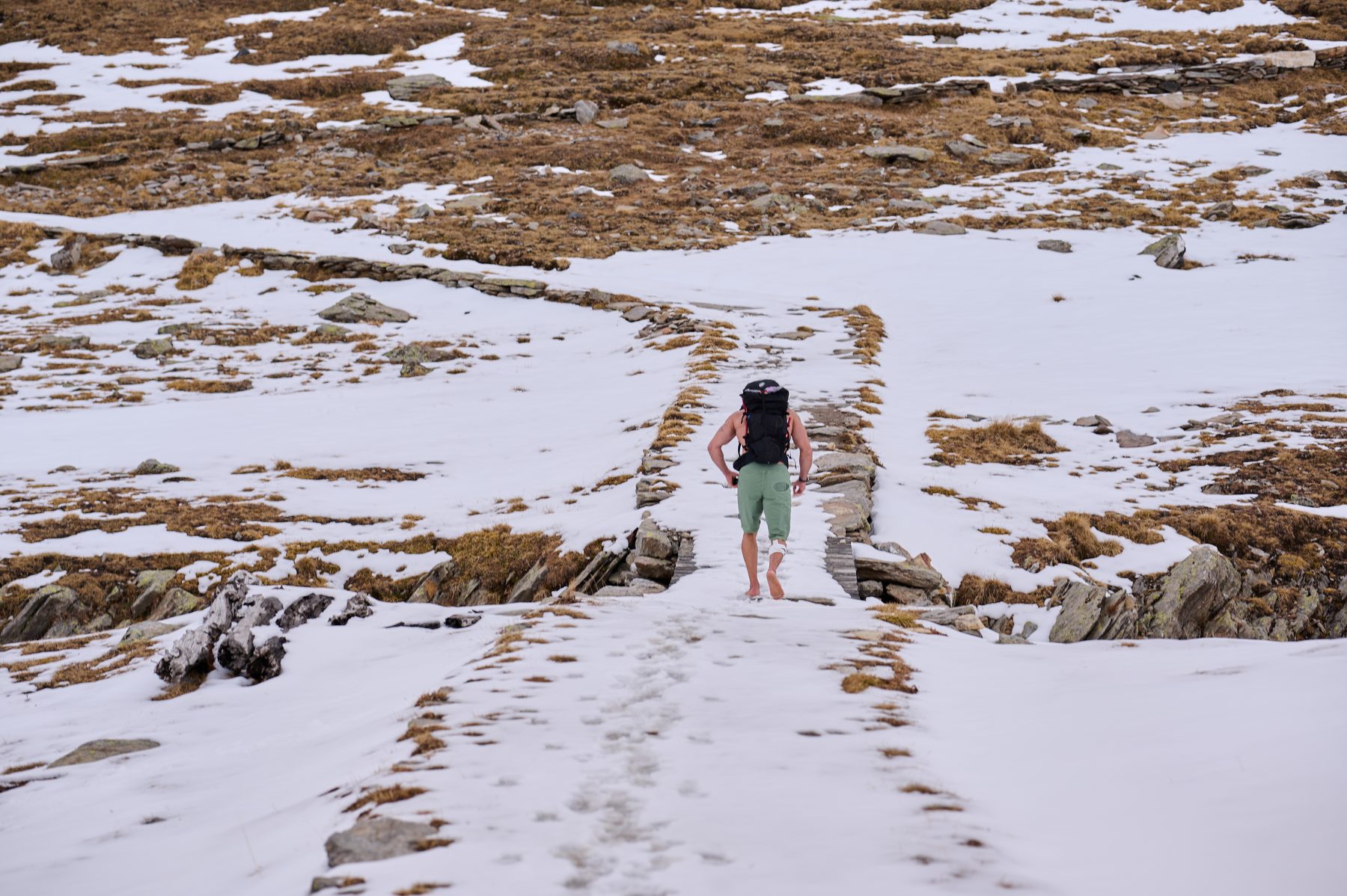 Claudio Lombardo cammina a piedi nudi sulla neve visto da dietro
