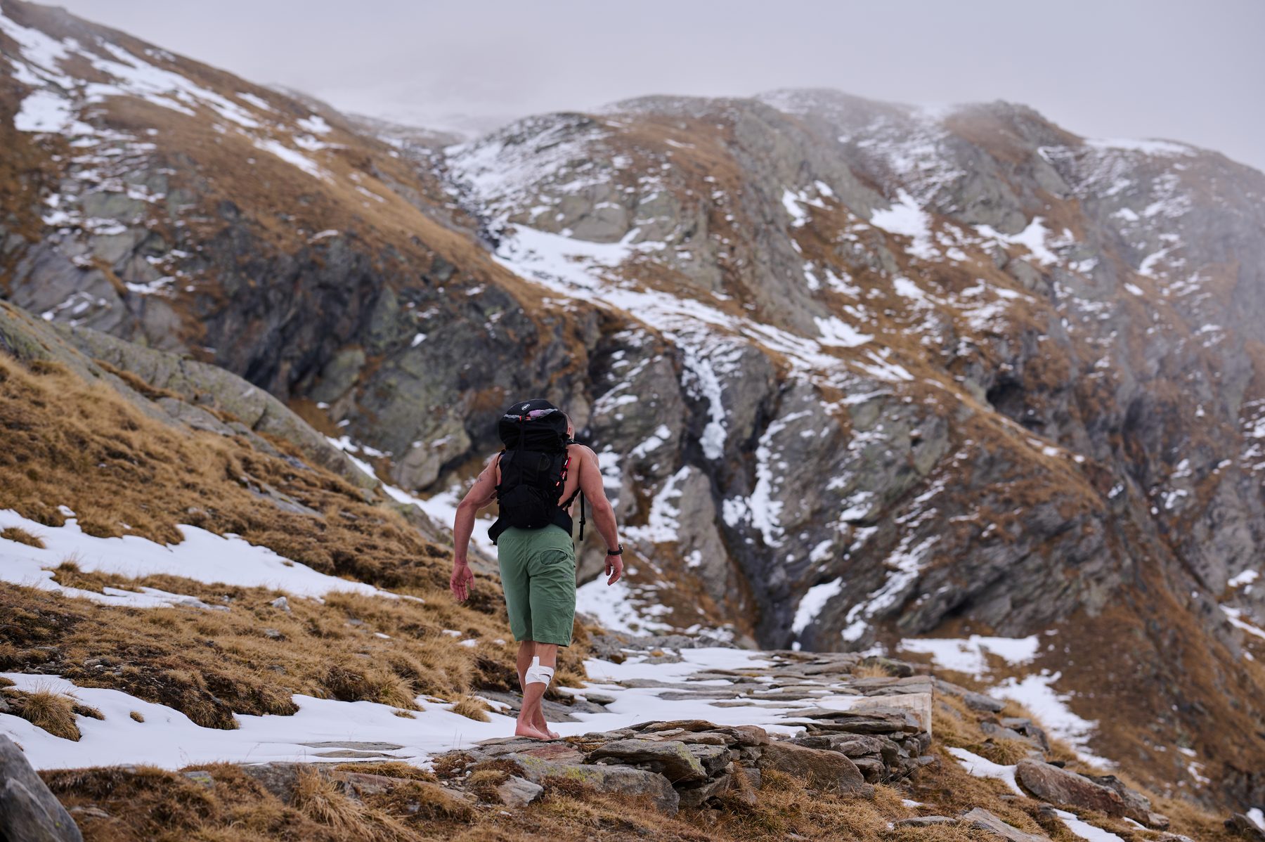 Claudio Lombardo percorre a piedi nudi un sentiero tra neve e roccia