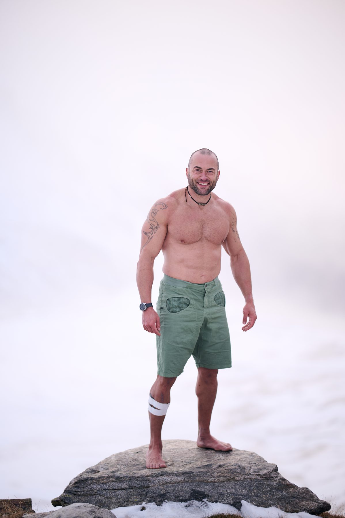 Ritratto verticale di Claudio Lombardo a piedi nudi su una roccia tra la neve