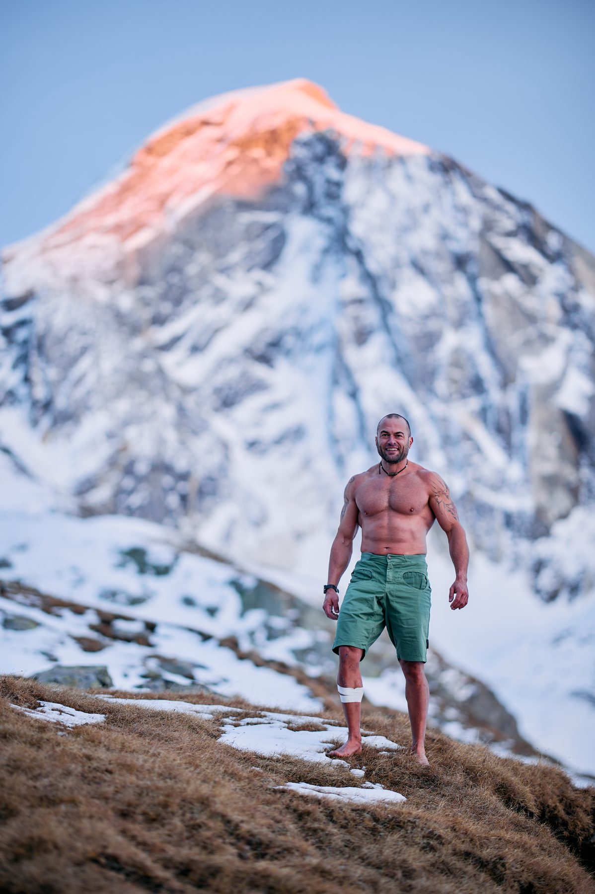 Claudio Lombardo a piedi nudi davanti a un’alta cima innevata illuminata dal sole