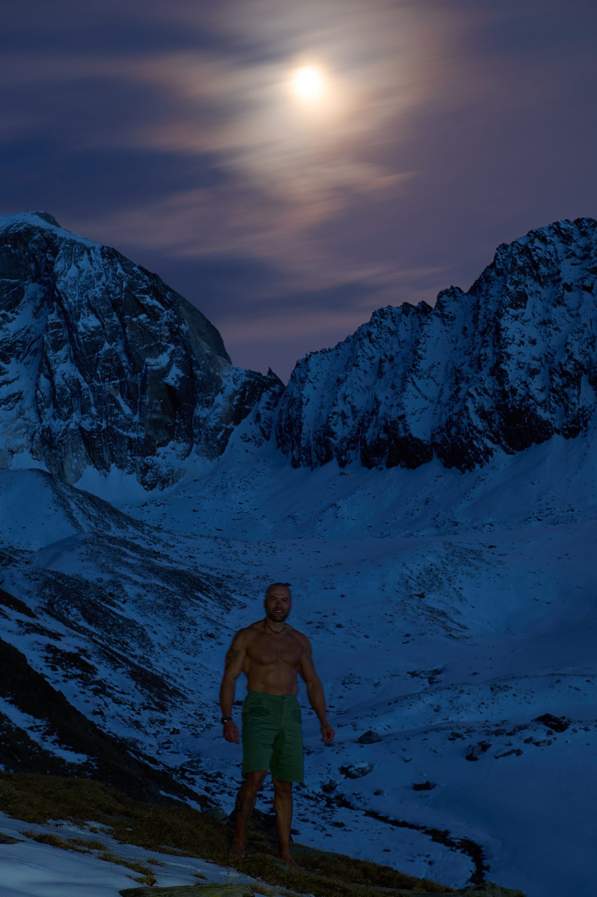 Claudio Lombardo in un paesaggio innevato al crepuscolo con la luna tra le cime